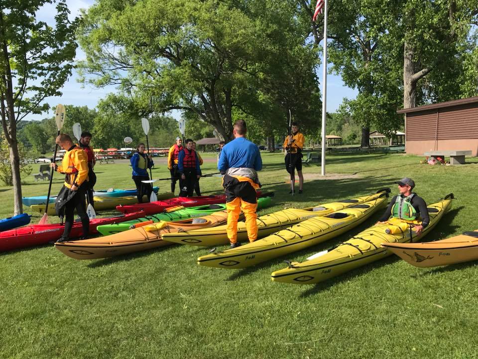 Find Hidden Gems of the Finger Lakes Region - The Long and Short of Paddling a group of people standing on kayaks